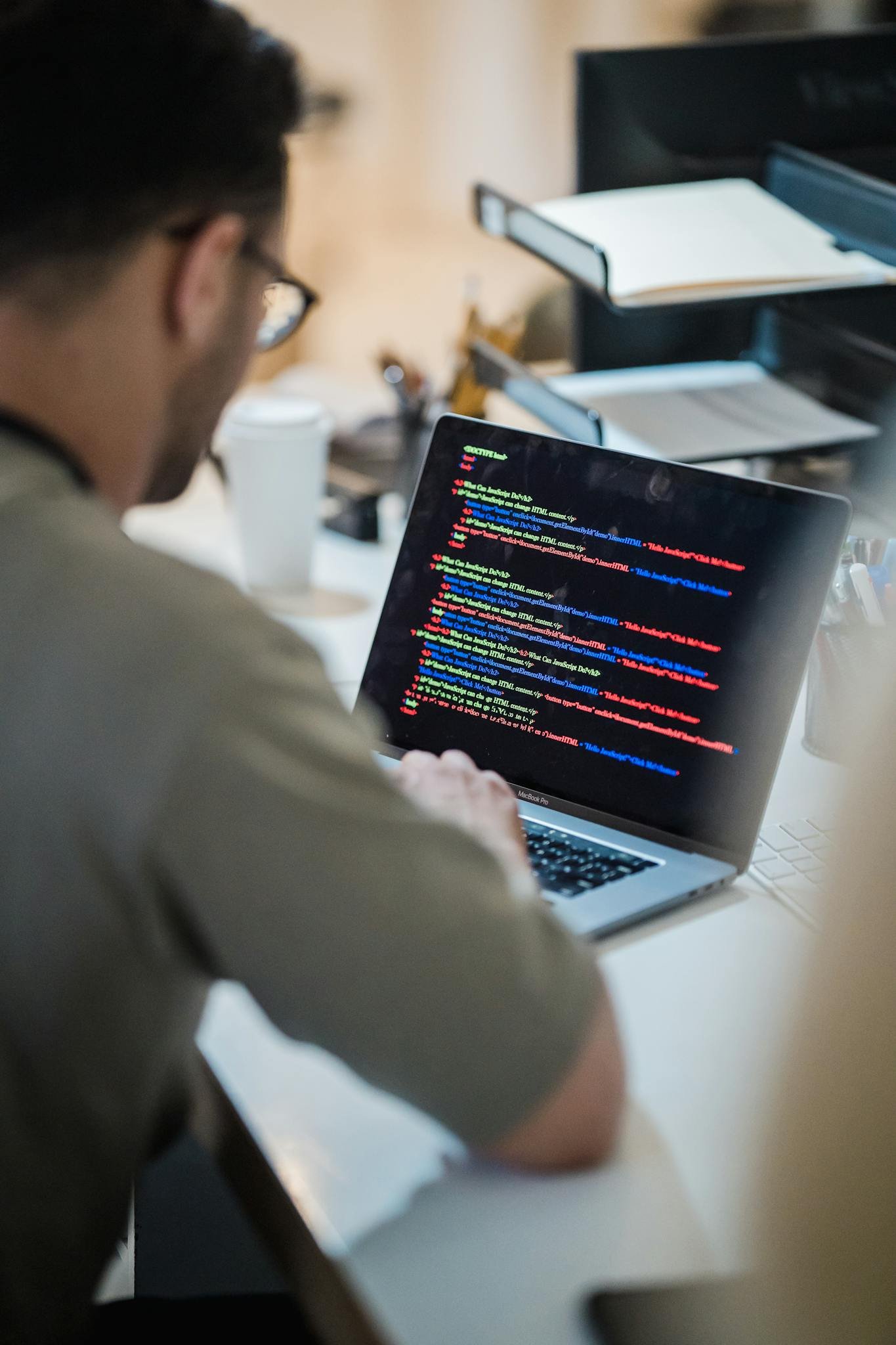 Home Focused programmer coding on a laptop in an office environment.