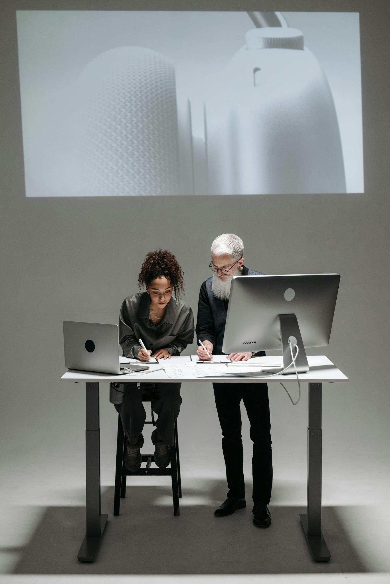 Home Two professionals collaborate in a high-tech setting with laptops and digital screens.